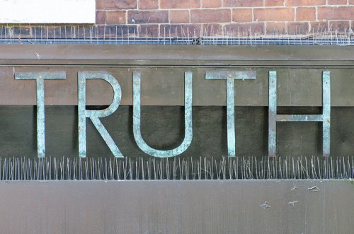 art installation of the word 'truth' in metal, surrounded by sharp nails