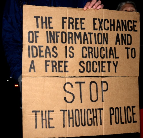 Cardboard sign at a rally reading "The free exchange of information and ideas is crucial to a free society. Stop the thought police."